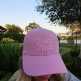 Woman wearing The Drink Pink Trucker Hat by Cold Beer Clothing Co., featuring pink embroidered Drink Pink lettering on the front in support of breast cancer awareness.